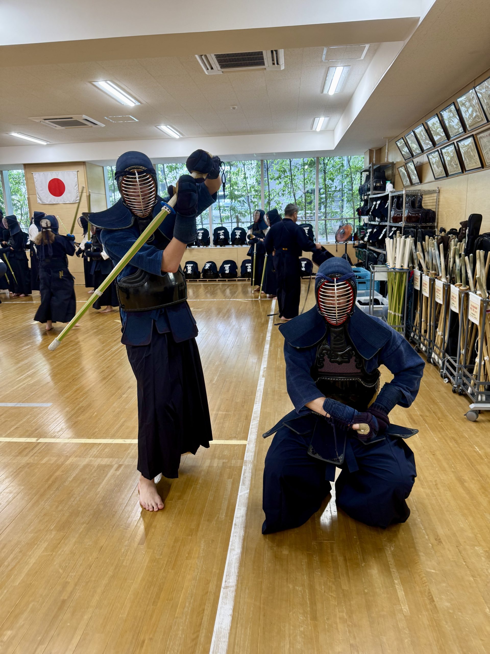 Students in kendo armor practice with bamboo swords in a training hall