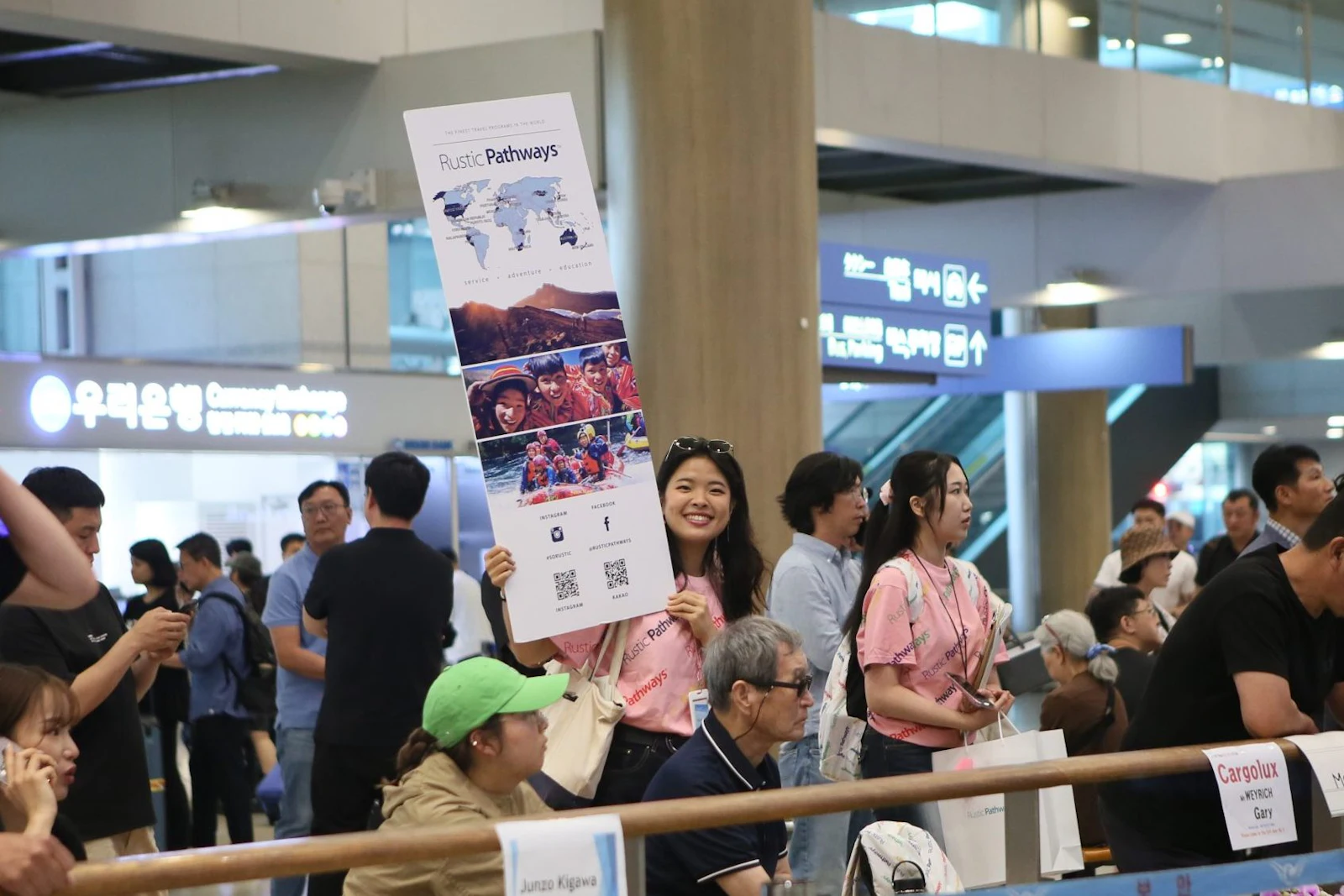 Rustic Pathways Program Leaders hold a welcome banner at the airport arrivals rail in South Korea