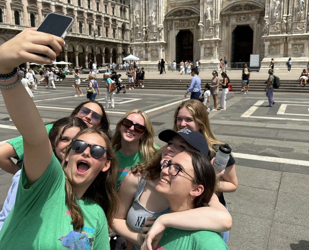 A group of teen travelers taking a selfie in a European town square.