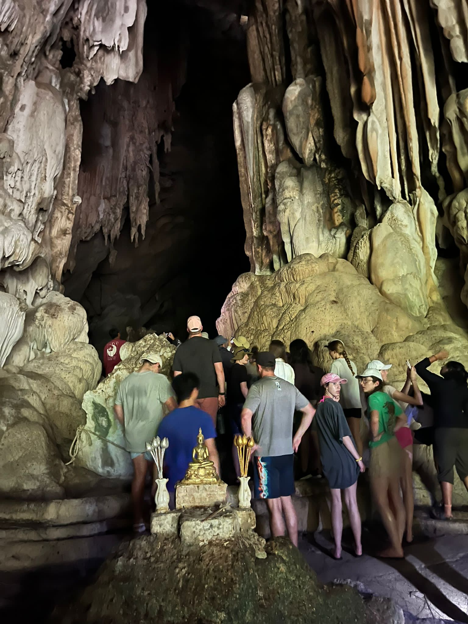 Students explore a limestone cave past a small shrine with incense