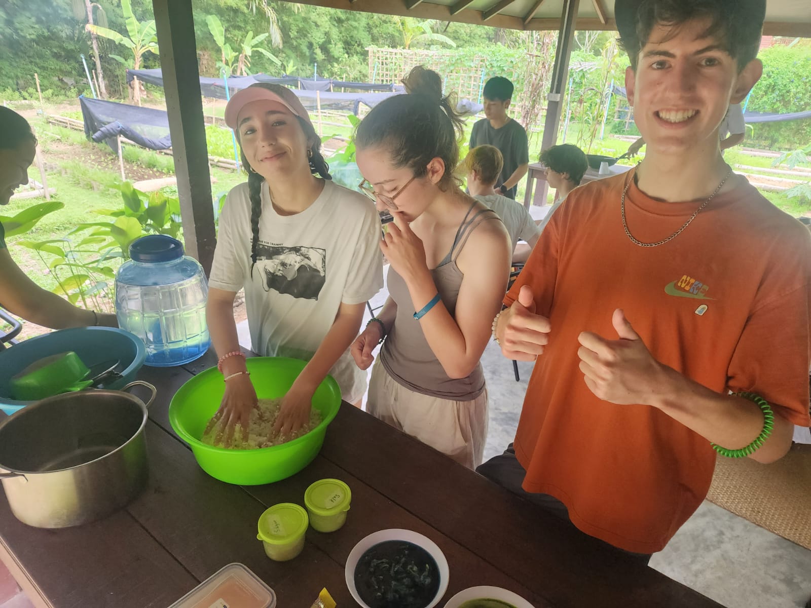 Students mix ingredients in a large bowl at an outdoor cooking table