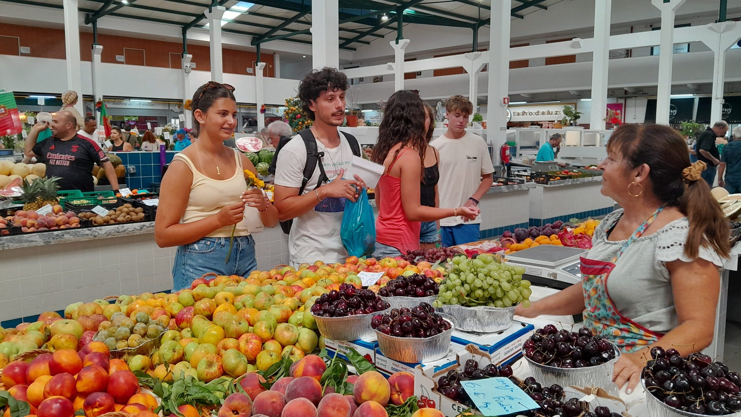 Teen travelers purchasing fresh produce from a market.