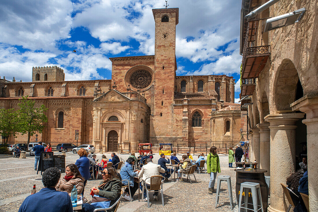 People sit at outdoor café tables in the Plaza Mayor of Sigüenza, Spain, below the town’s medieval cathedral