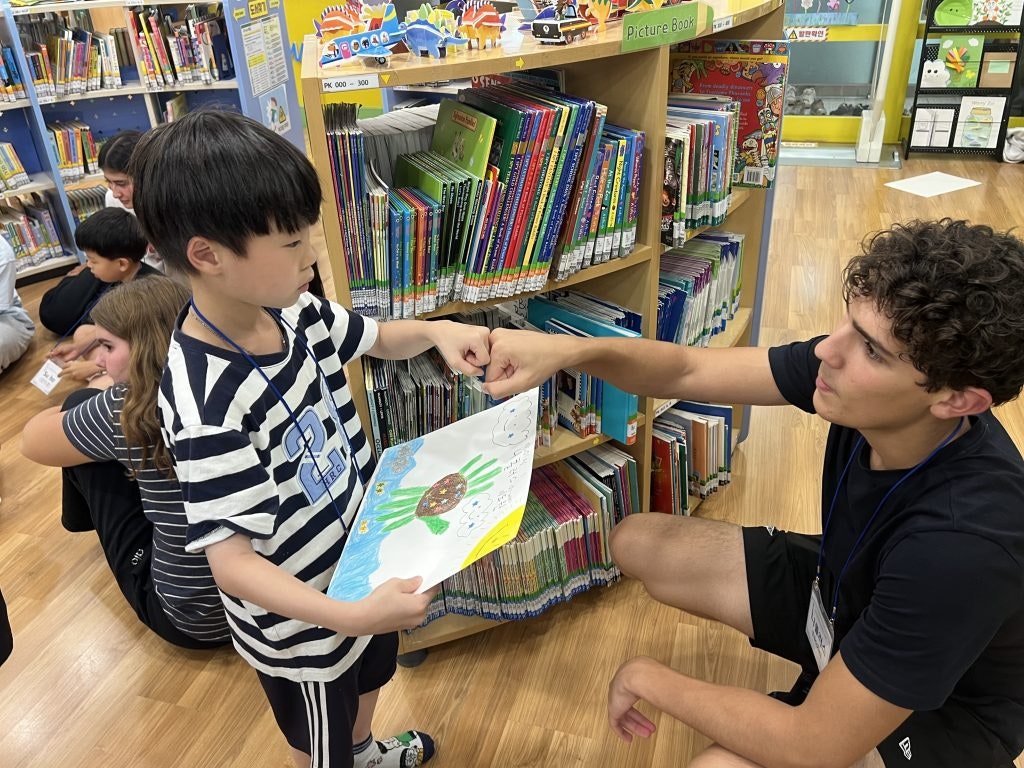 A teen and a local Korean kid interacting during an English conversation class hosted by Rustic Pathways students.