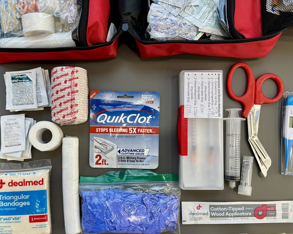 Contents of a Rustic Pathways program leader med kit laid out including bandages gauze gloves antiseptic and various medicines. 