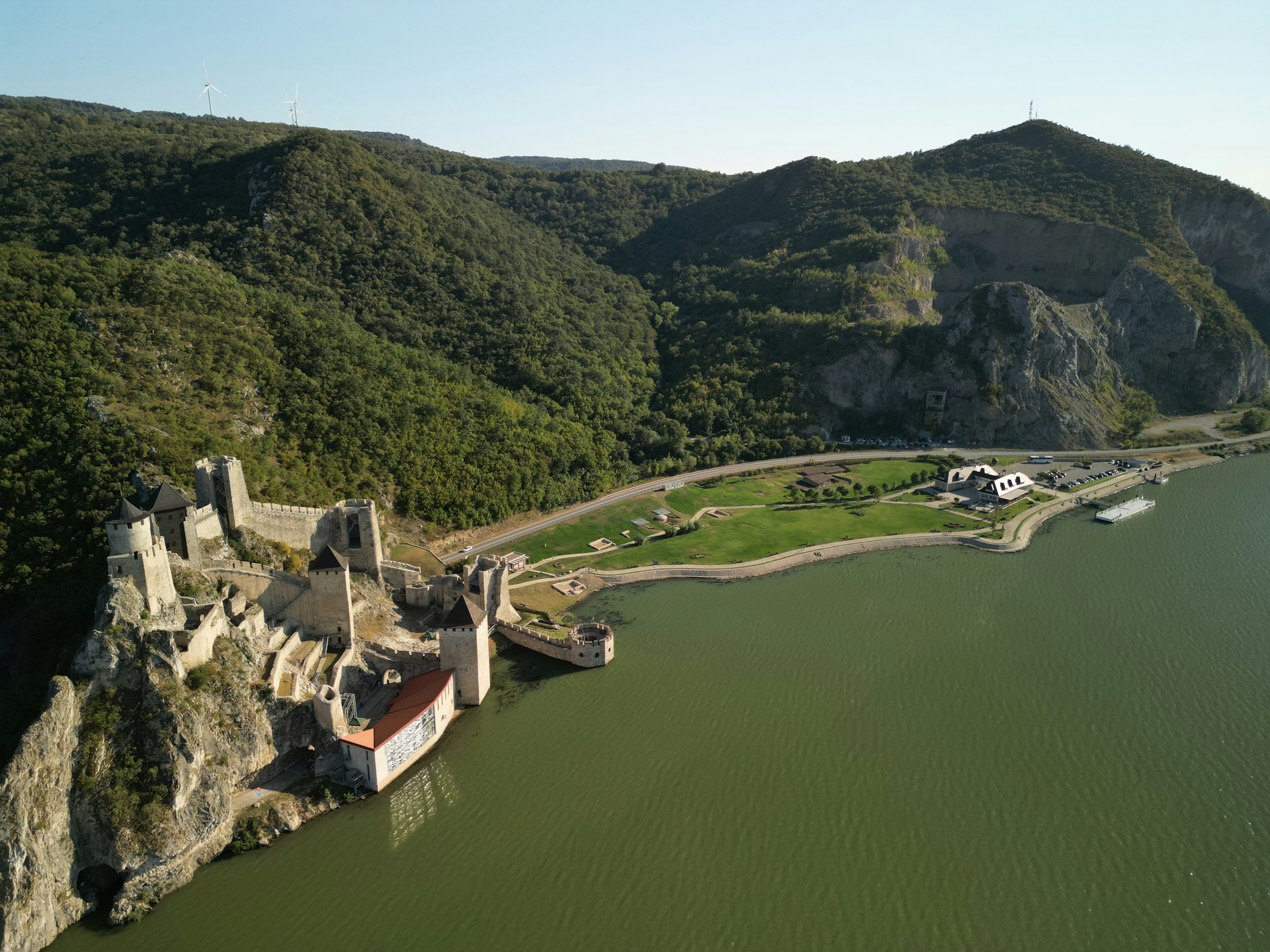 A turreted medieval river fortress sits on a rocky point where a cliff meets the Danube, seen from above.