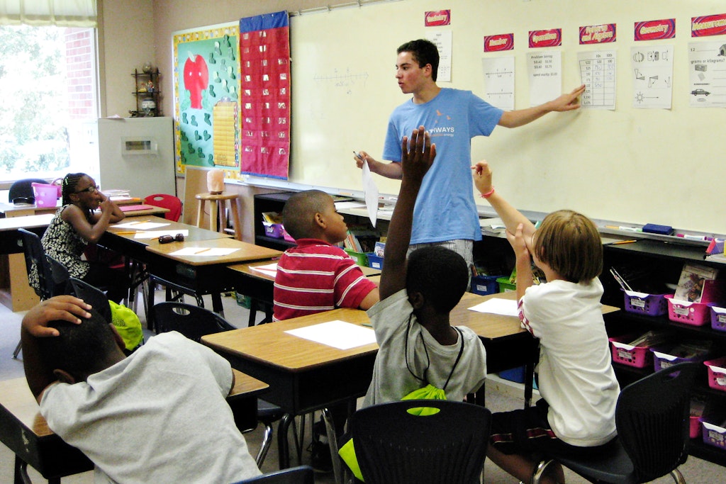 Teen volunteer abroad program participant teaching students in a classroom as part of an international education project.