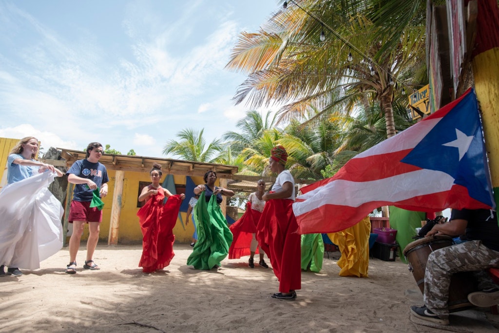 Group performing traditional dance with Puerto Rican flag on a sunny day