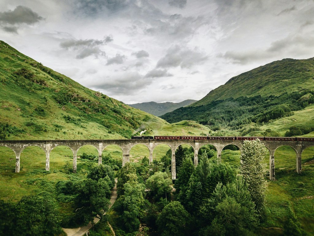 Picture of viaduct in Glenfinnan, Scotland with hills in the background and grey sky. Fun facts about edinburgh
