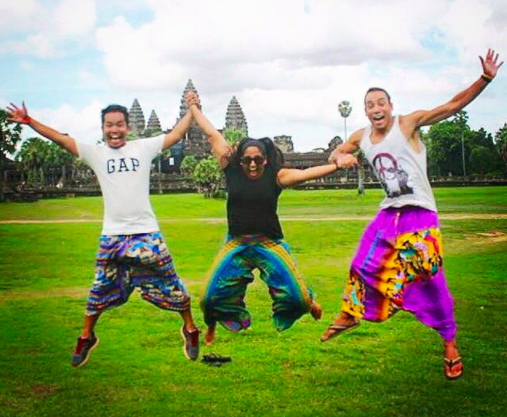 Three friends jumping and holding hands in front of Angkor Wat.