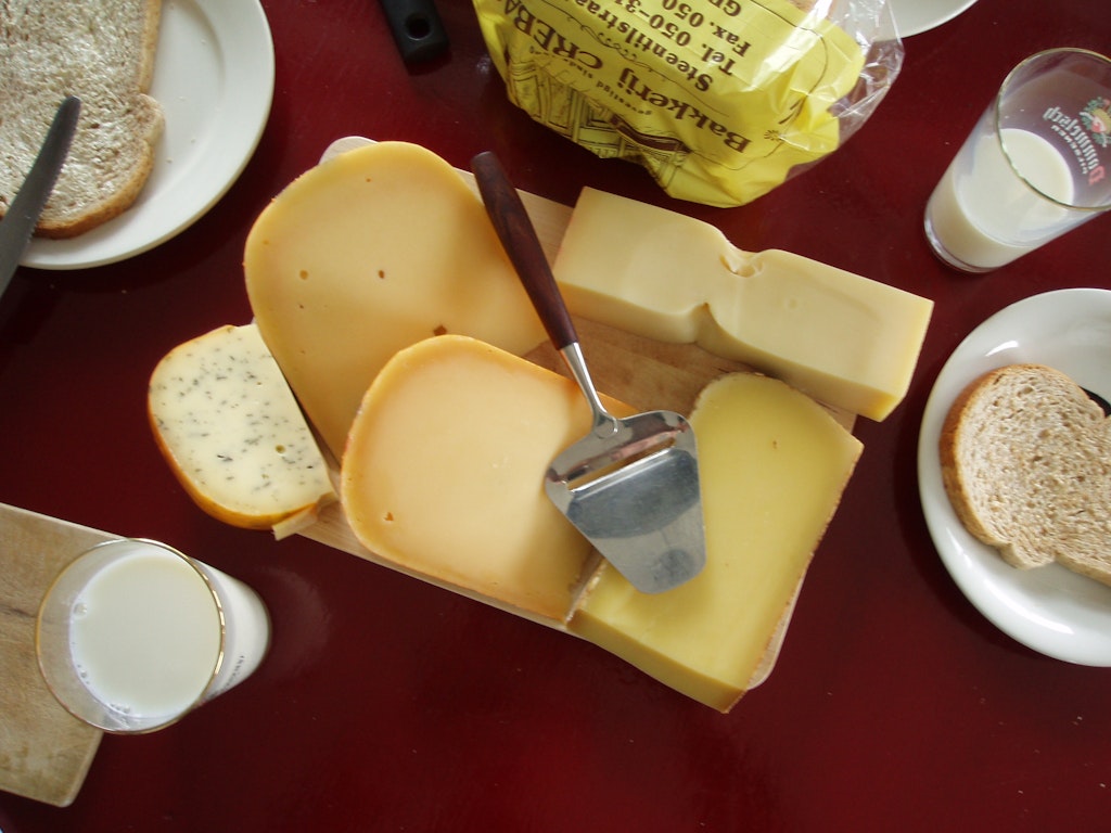 Photo of a classic cheese slicer laying on top of white cheeses