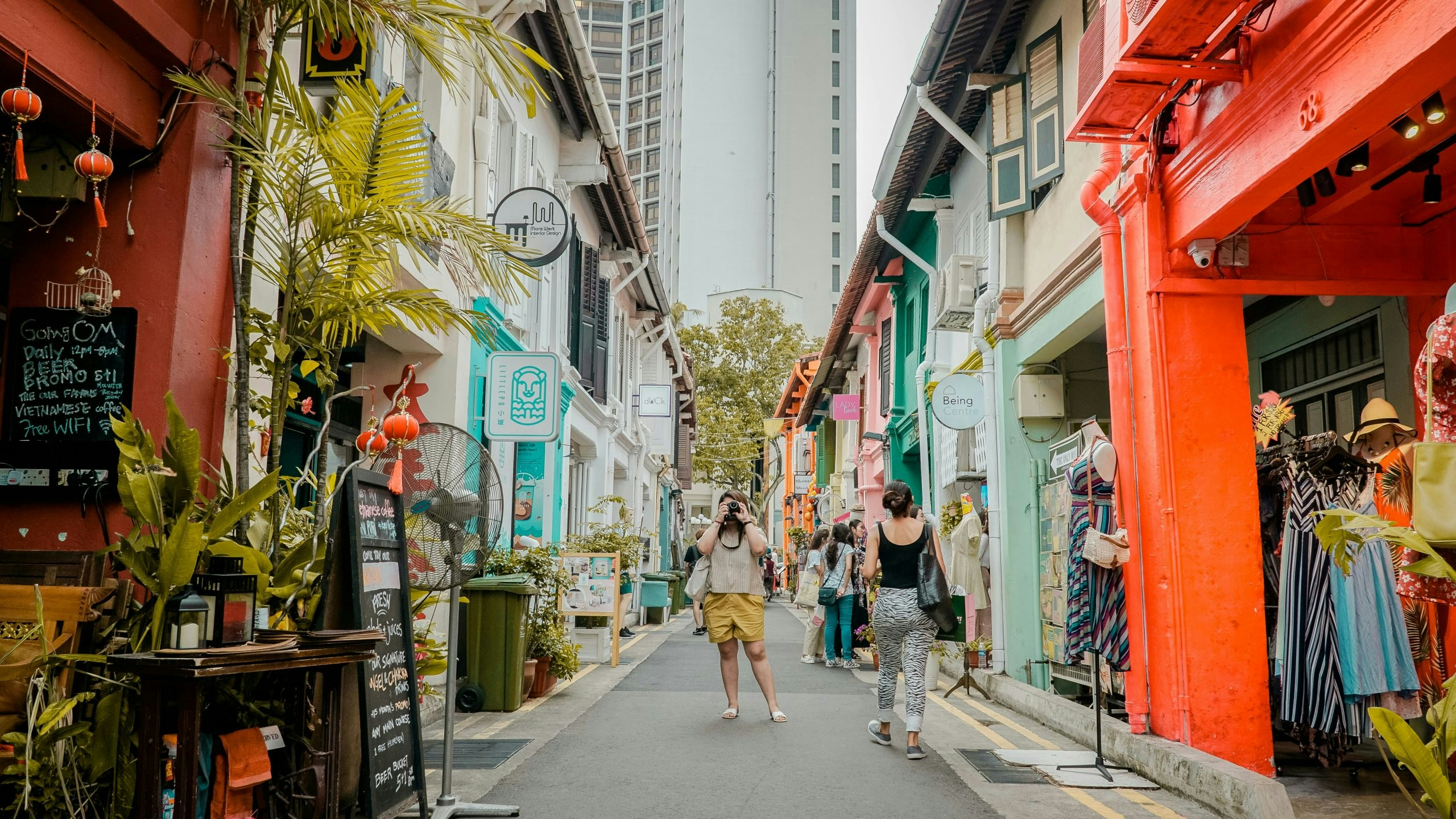 Shopping street in Singapore with a women taking a photo in the center of the street.