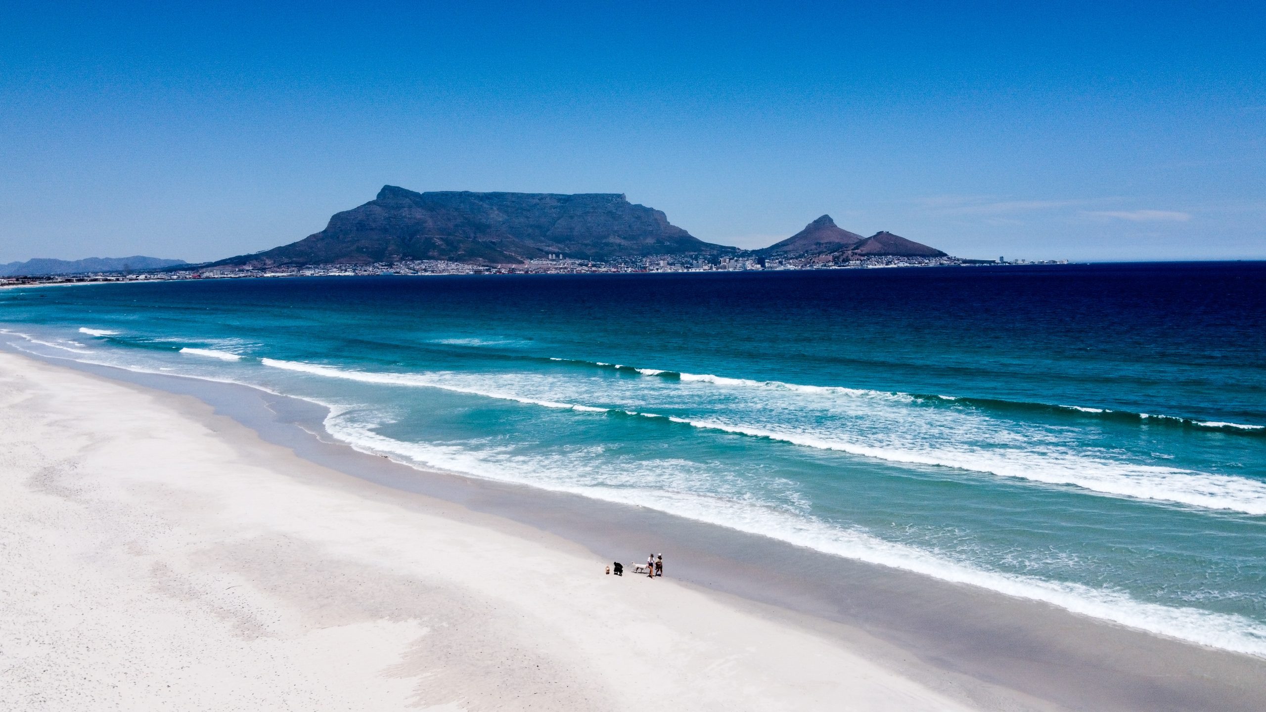 On a school trip, students take in Table Mountain rising above Cape Town's coastline from a wide sandy beach