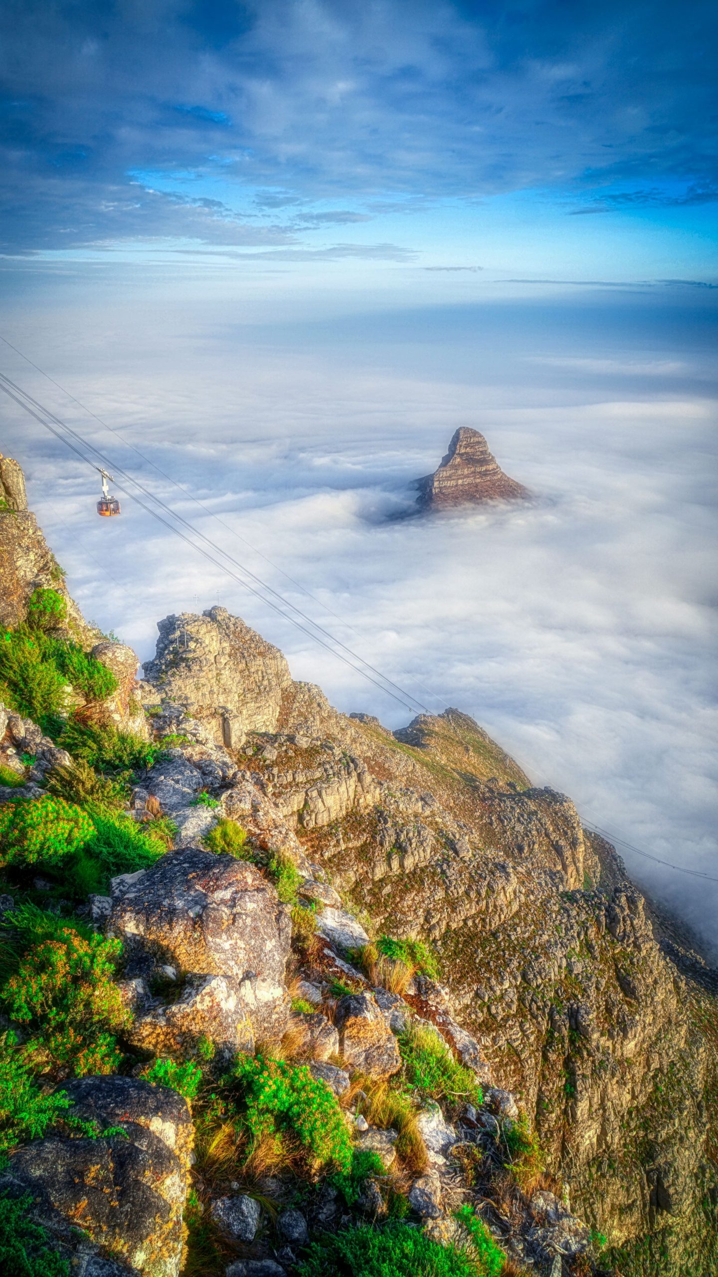 A cable car descends a rocky ridge above a sea of clouds on Table Mountain