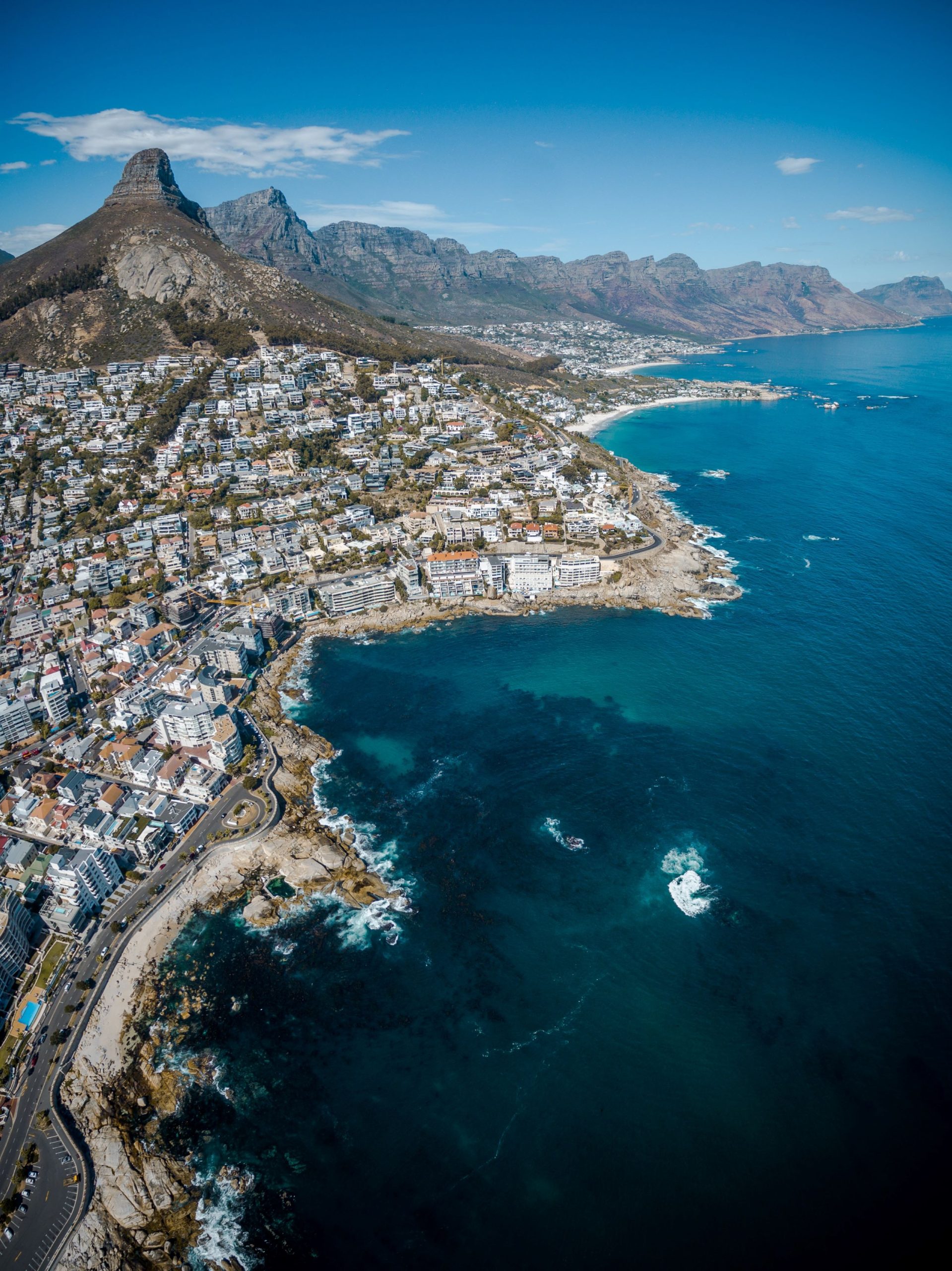 Mountains rise above Cape Town's coastline in South Africa, with clear blue water along the shore