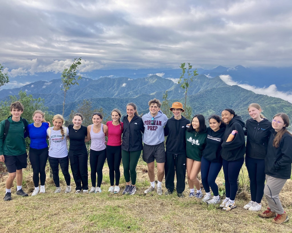 Student travelers in Ecuador posing for a photo with a mountain range behind them.