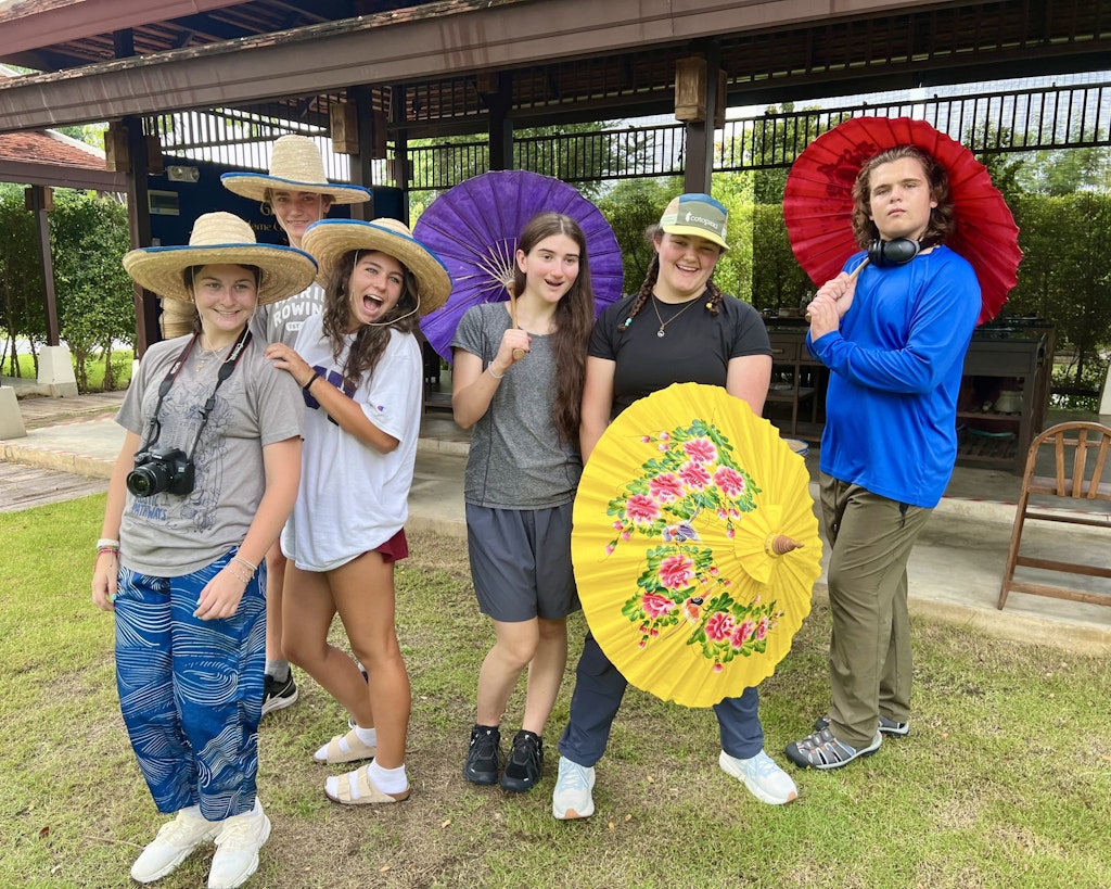 Students on a low program cost student travel program in Thailand posing for a photo with traditional umbrellas.