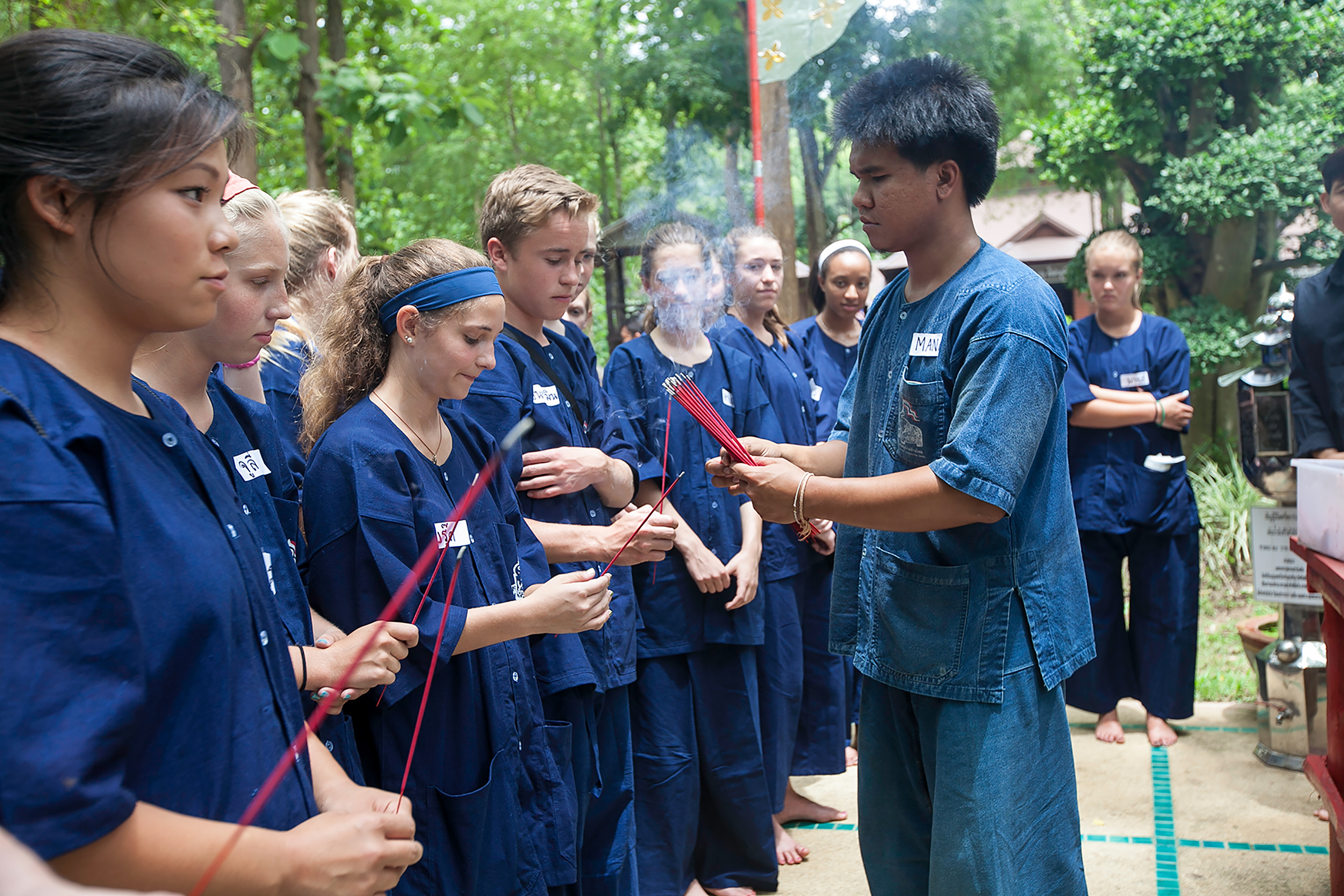 Students gathered receiving incense stick from instructor.