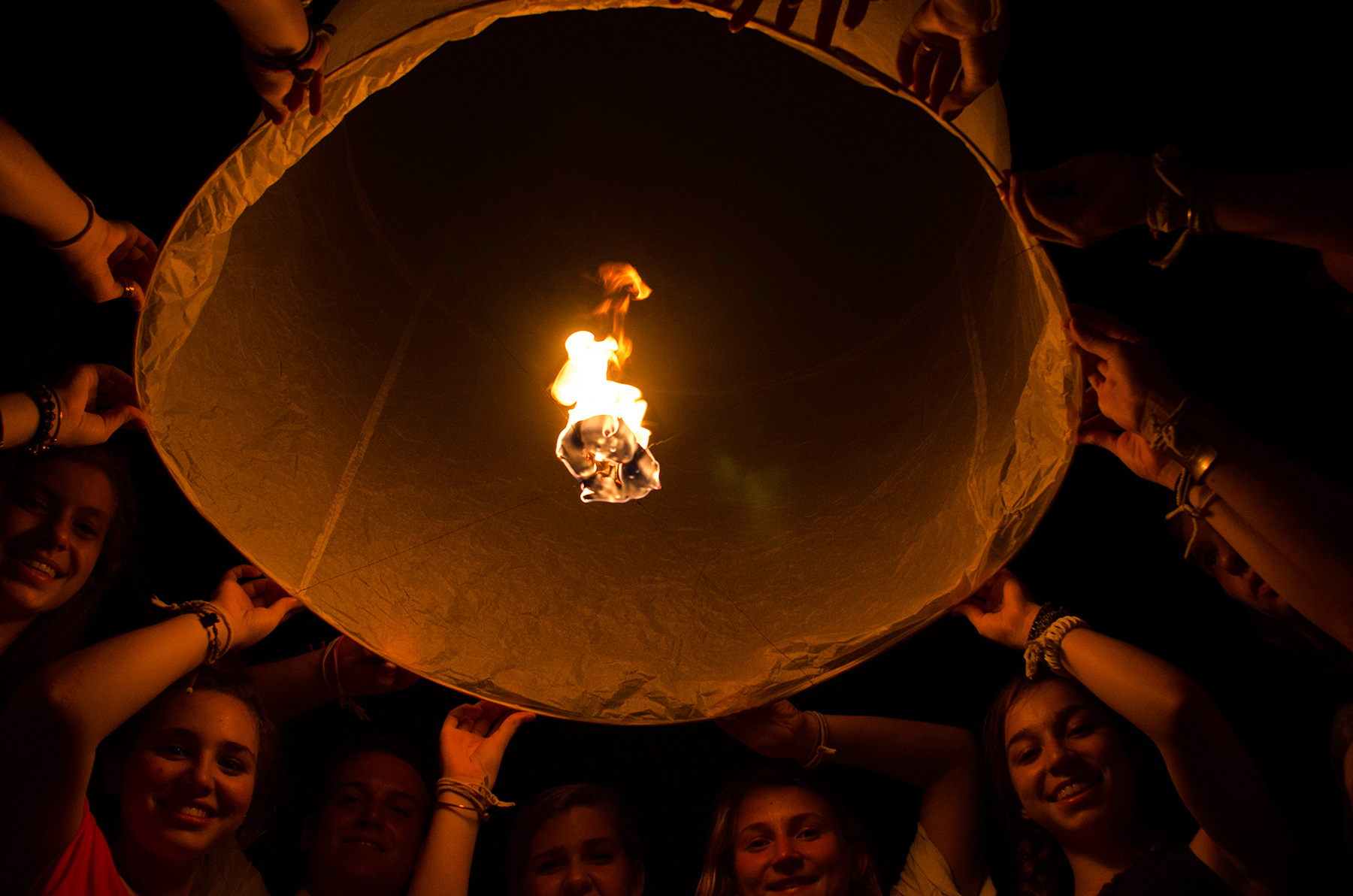 Students hold up a glowing sky lantern at night
