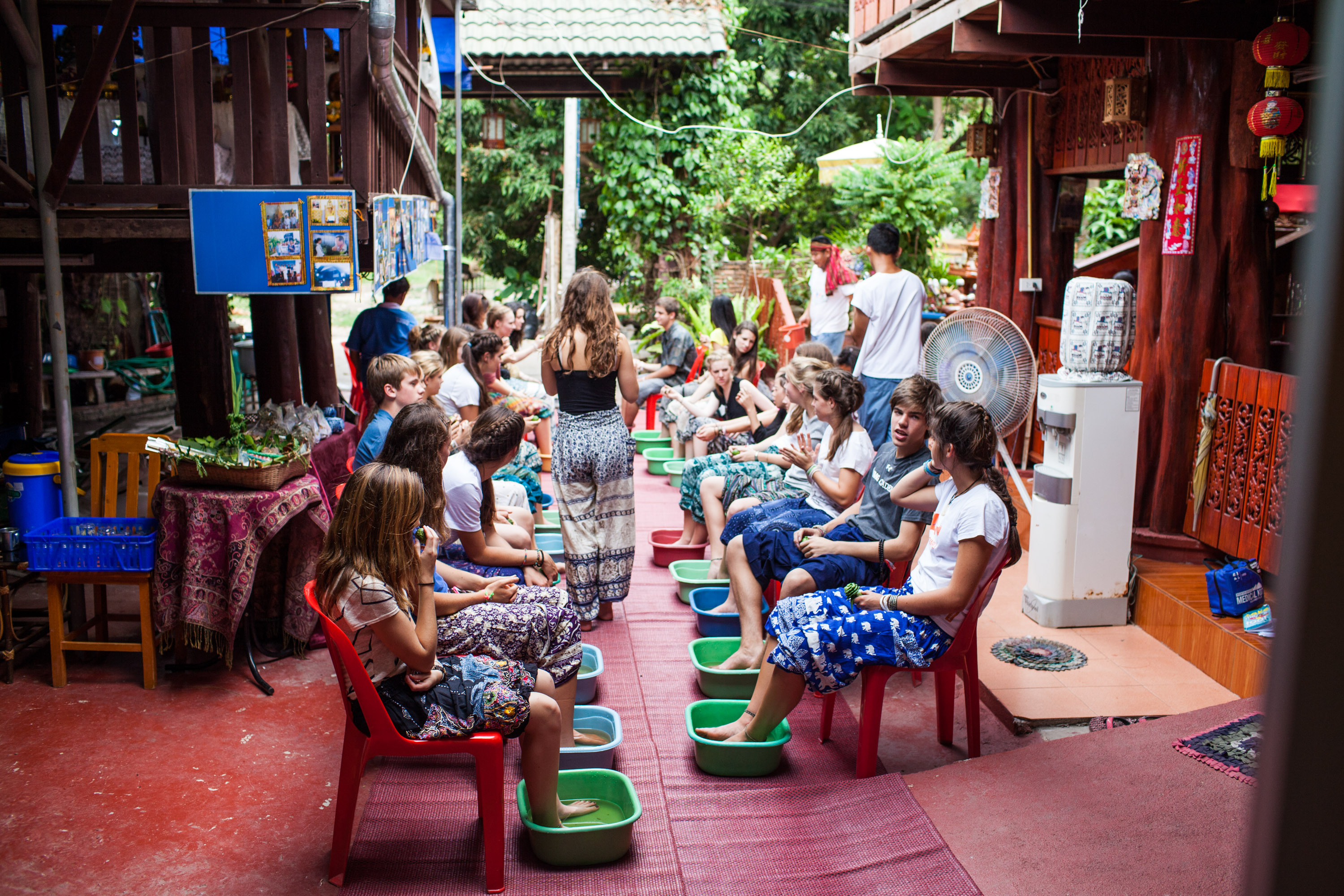 Students sit in rows with their feet soaking in basins during a foot bath
