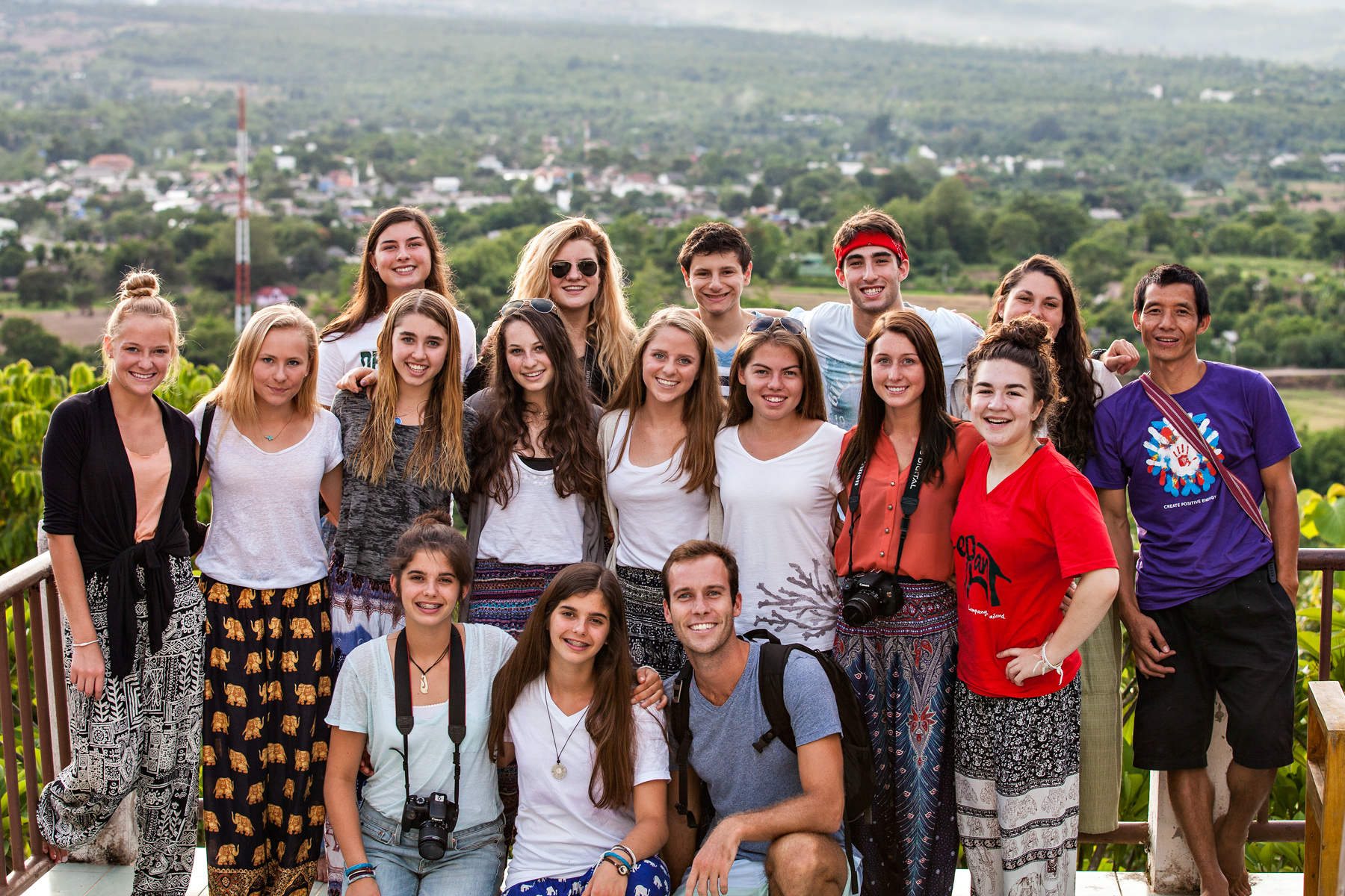 Students pose together on an overlook with green countryside stretching behind them
