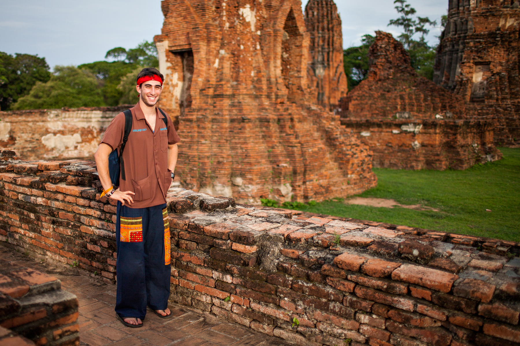 A student stands beside ancient brick ruins at a Thai temple
