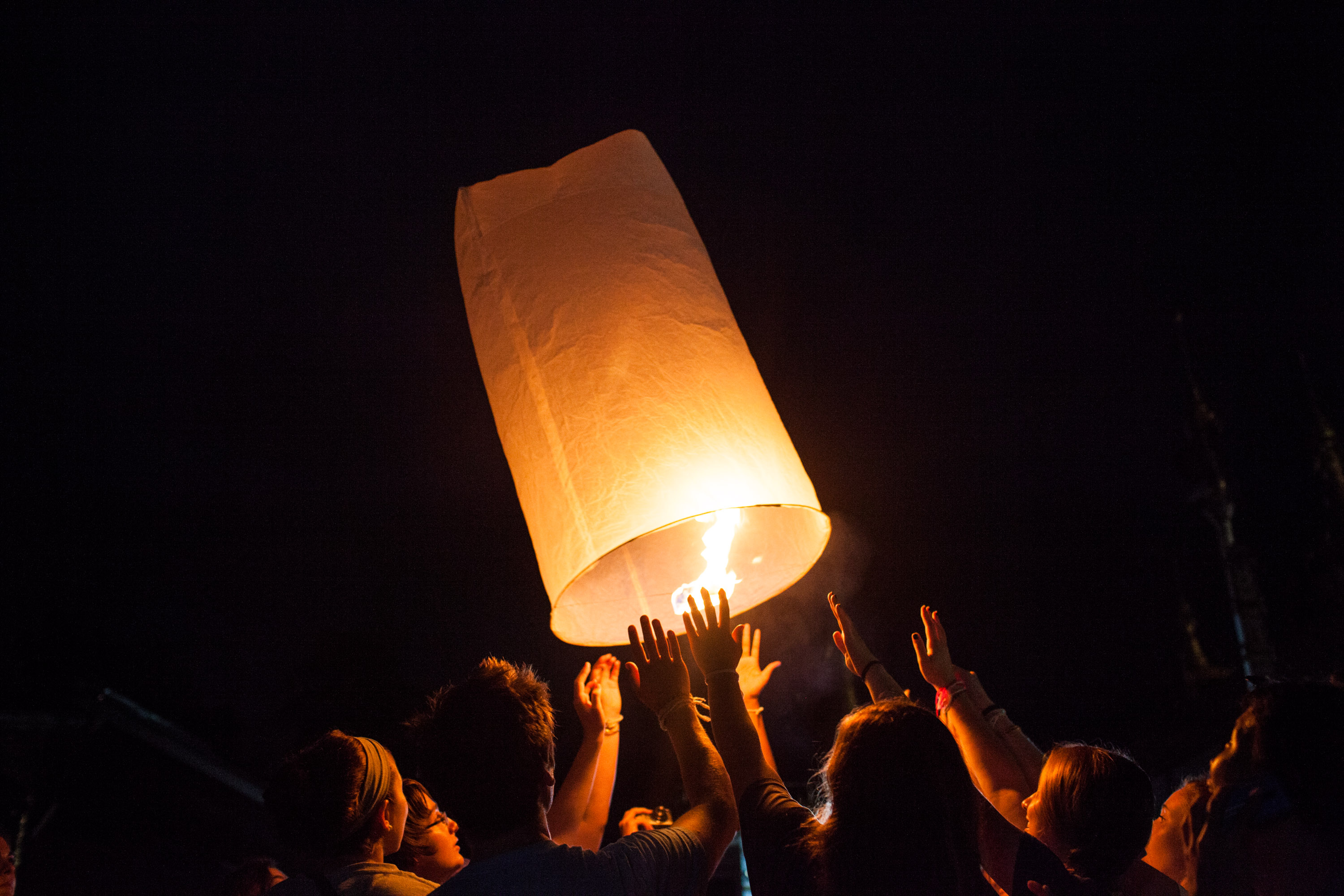 Students release a glowing lantern into the night sky