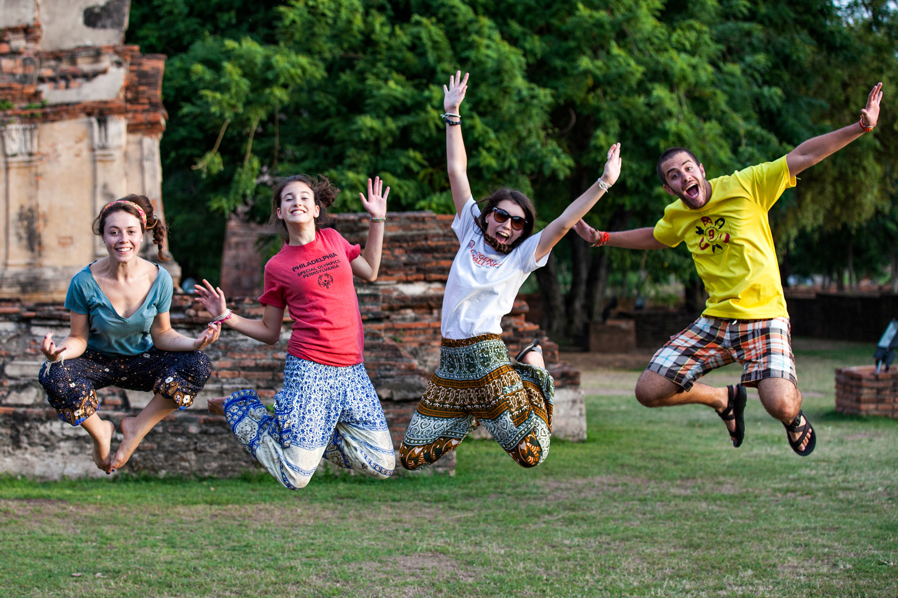 Student travelers jump for joy in front of ancient temple ruins in Thailand