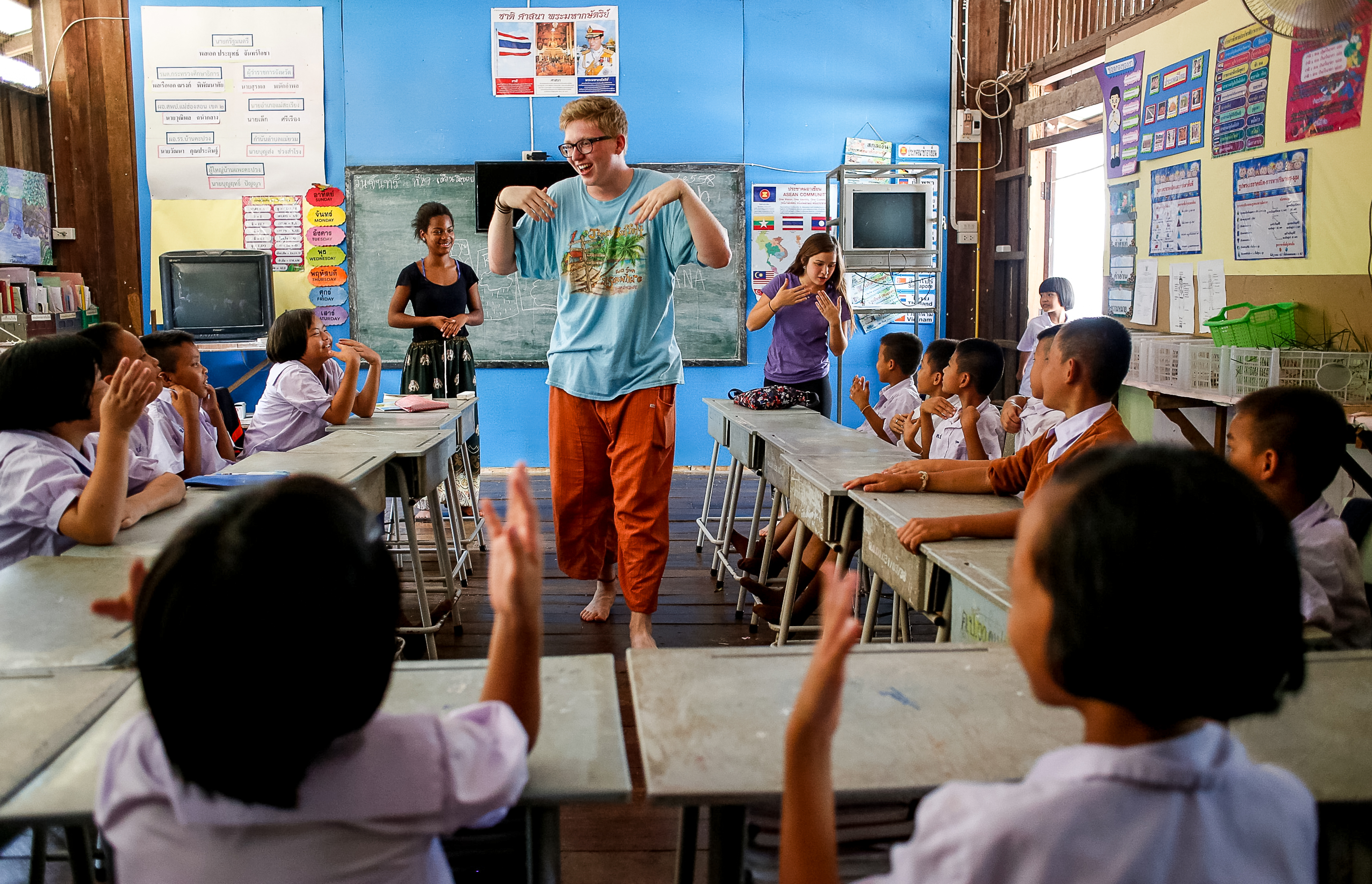 A student leads a game in front of a classroom of Thai schoolchildren
