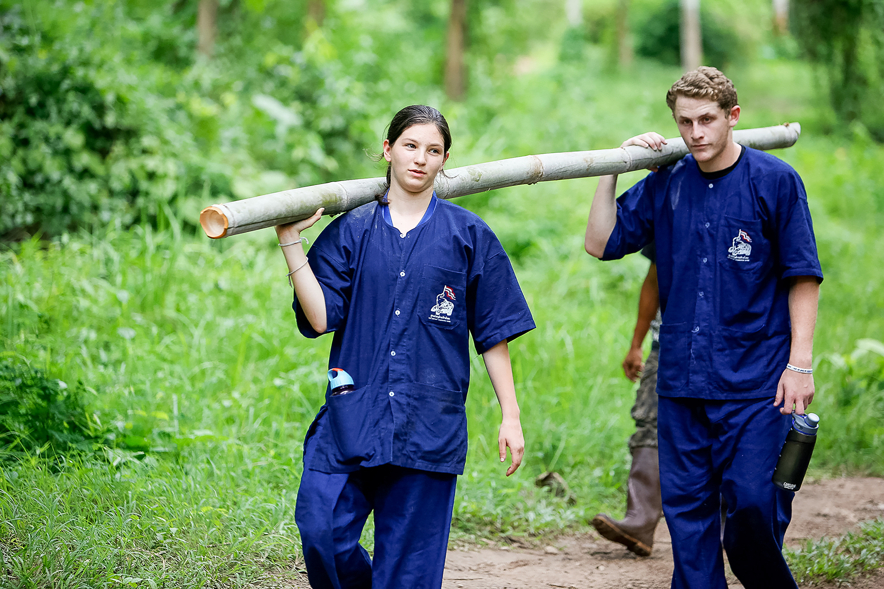 Students in Thailand carrying a log on their shoulders.