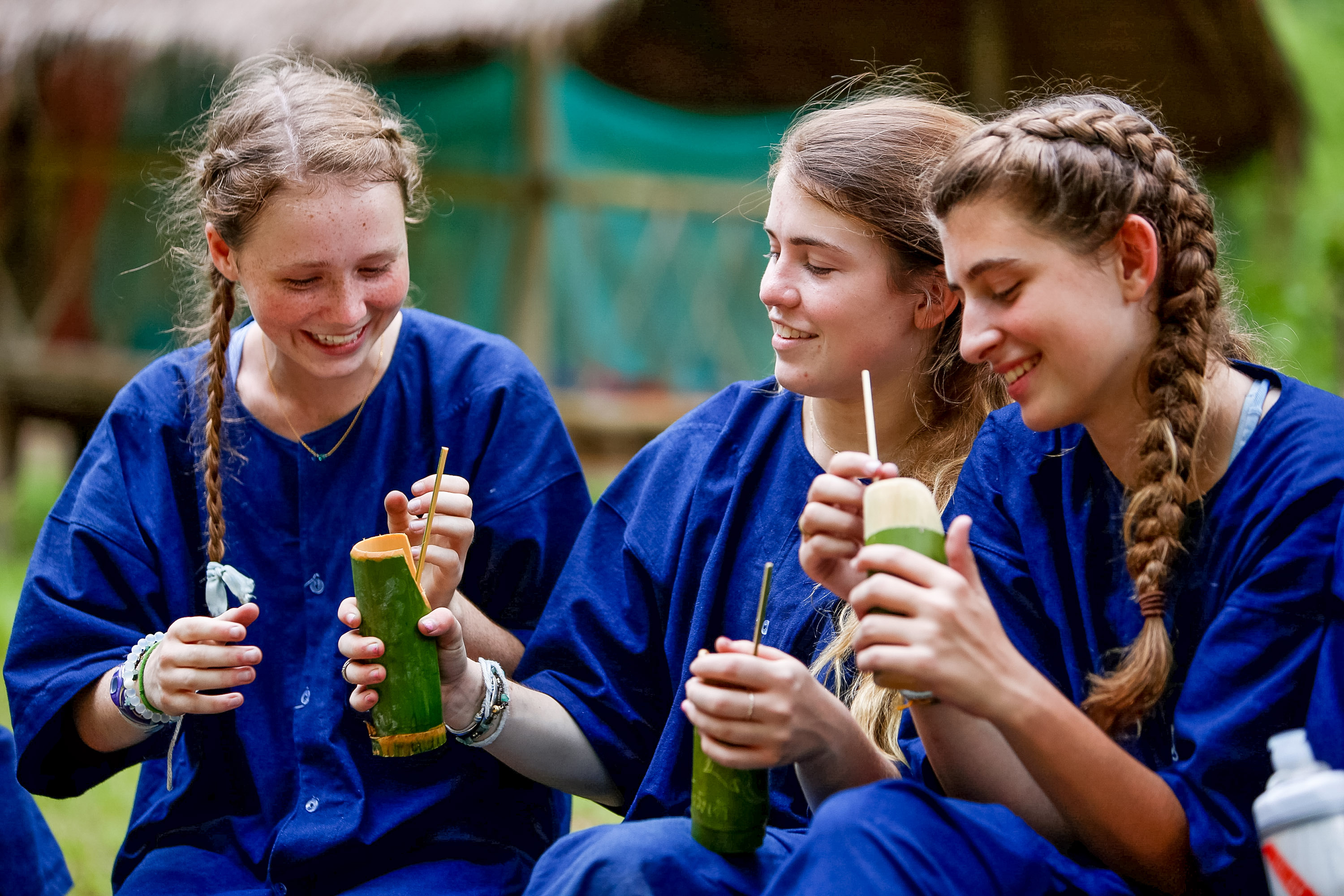 Students laugh while sipping drinks from carved bamboo cups