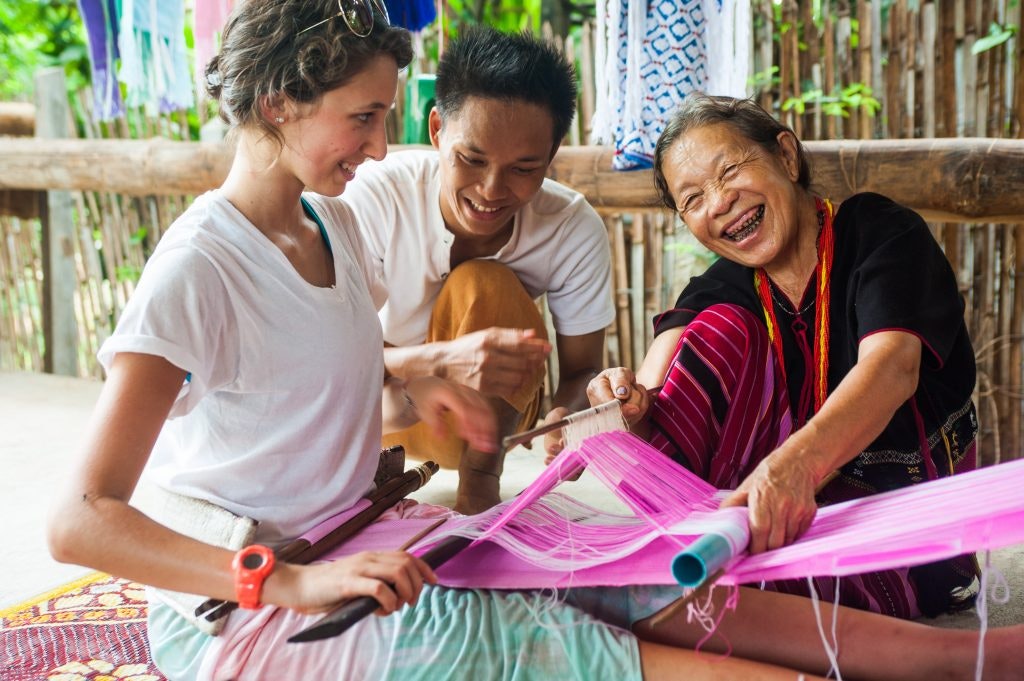 A student learns the art of fabric weaving from local experts.