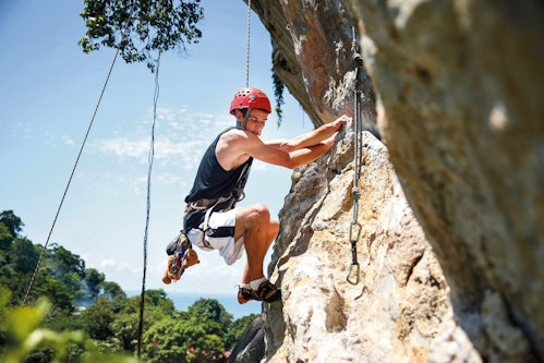 Teen adventure traveler rocking climbing on the cliffs in Southern Thailand
