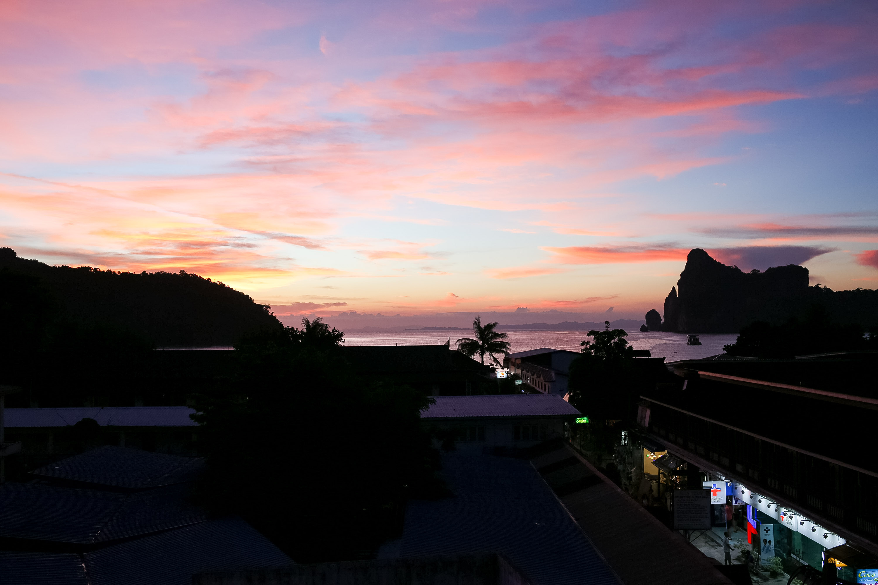 Students watch a pink and orange sunset over island silhouettes and a coastal town