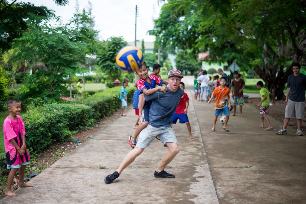 Children and teens play with a ball on the street.