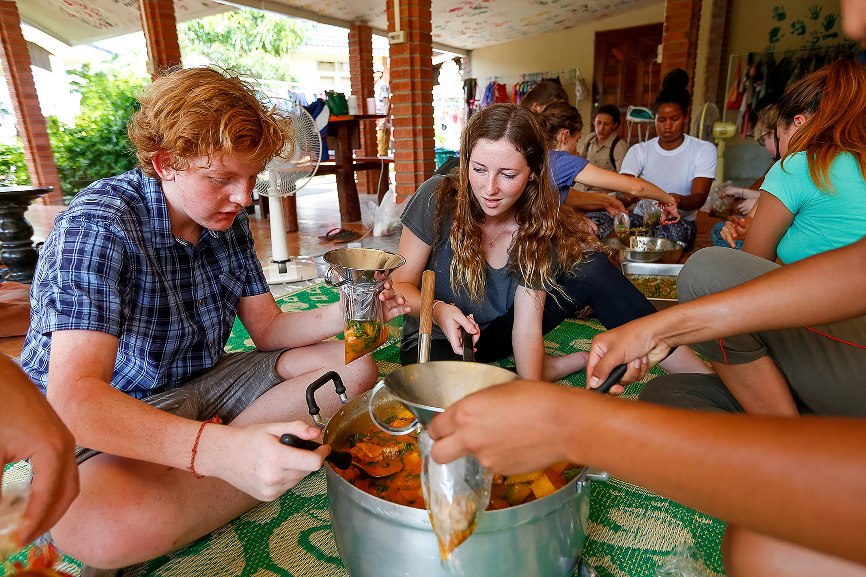 Students bag portions of soup from a large pot during a cooking class