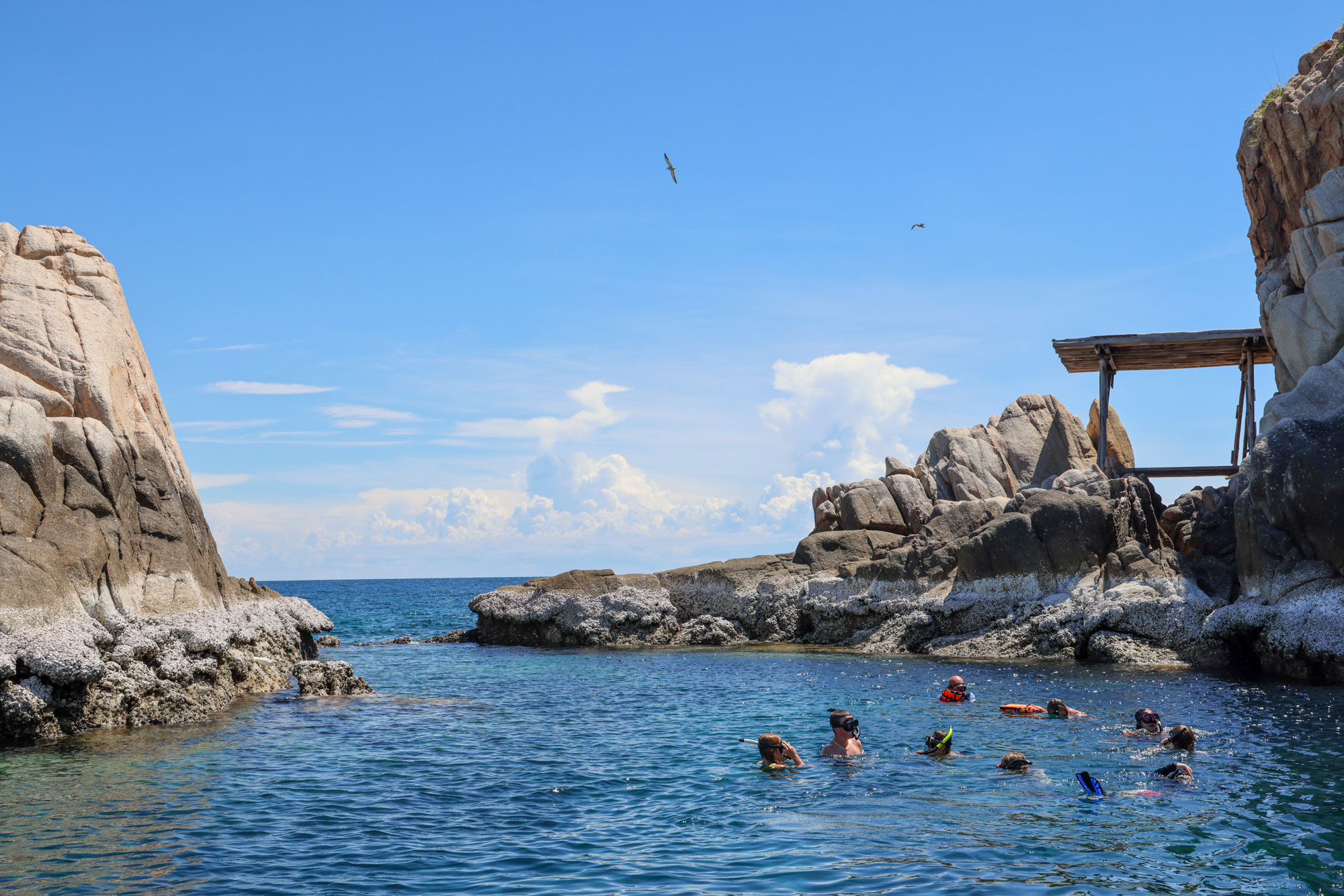 Student travelers snorkel in a rocky lagoon along the Andaman Sea coastline