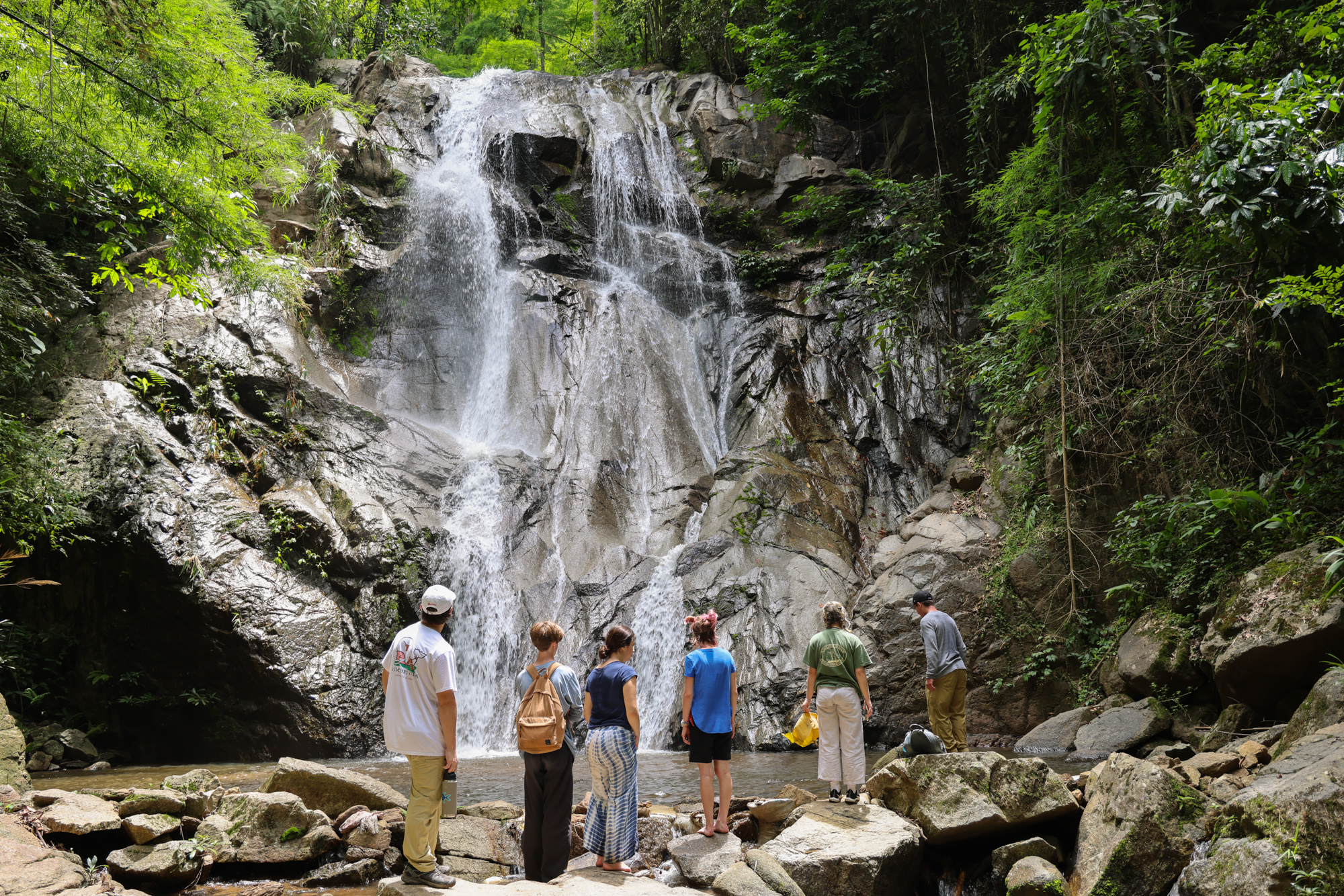 View of students staring at waterfall in Thailand.