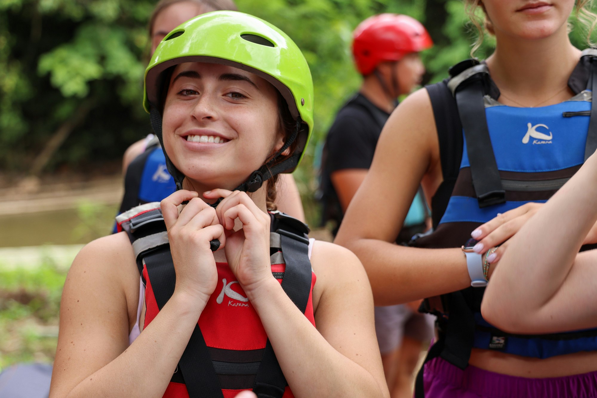 Smiling student putting on a helmet before going rafting in Thailand.