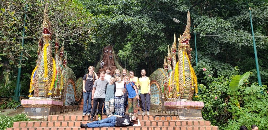 A group of teen tour participants pose together at a the entrance of a temple in Thailand.