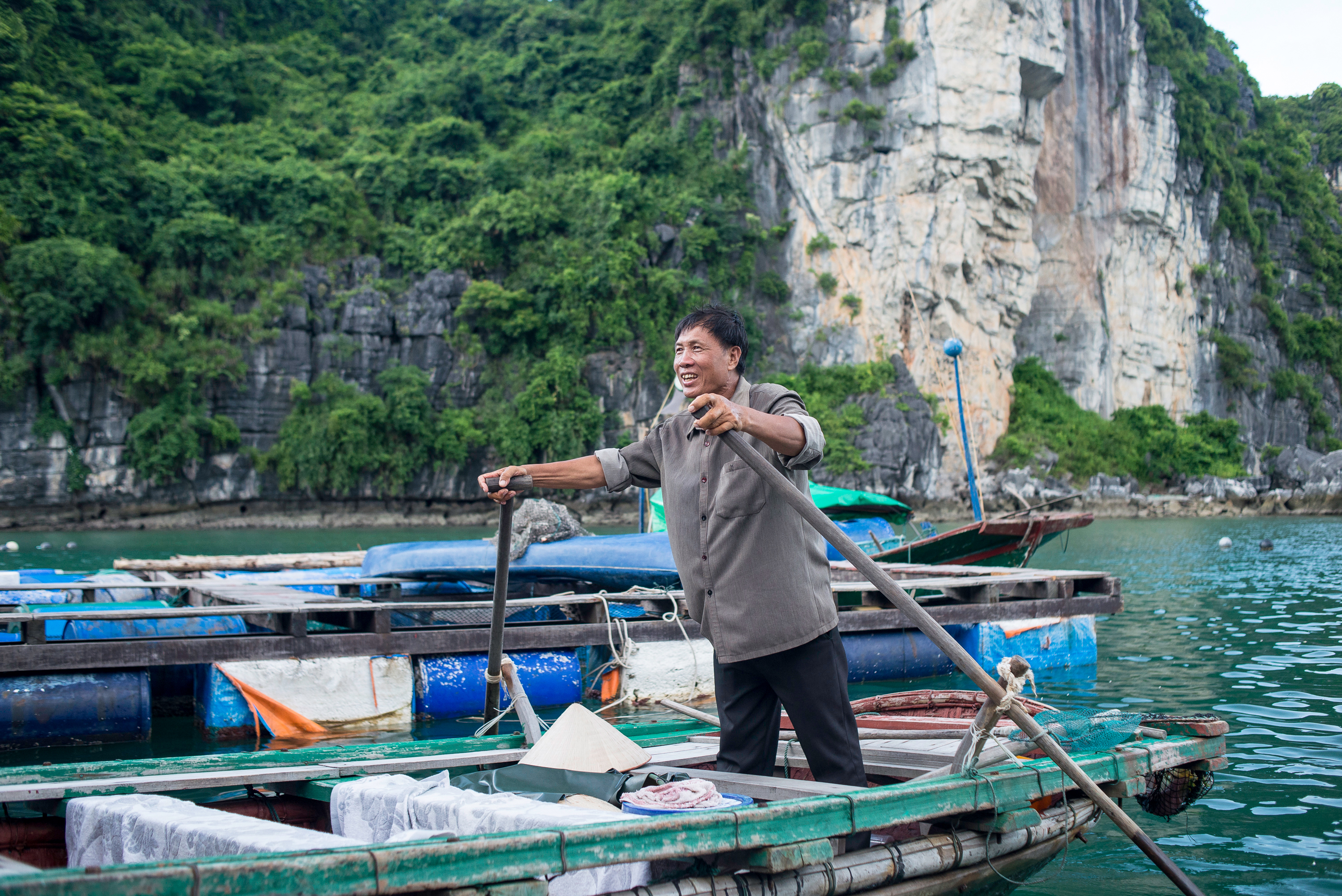 A boat operator rows among limestone karsts in Ha Long Bay