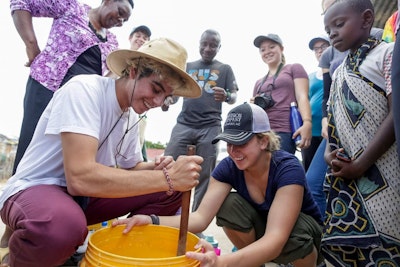 Two students assist local villagers in Tanzania during a service project on a teen tour in Africa