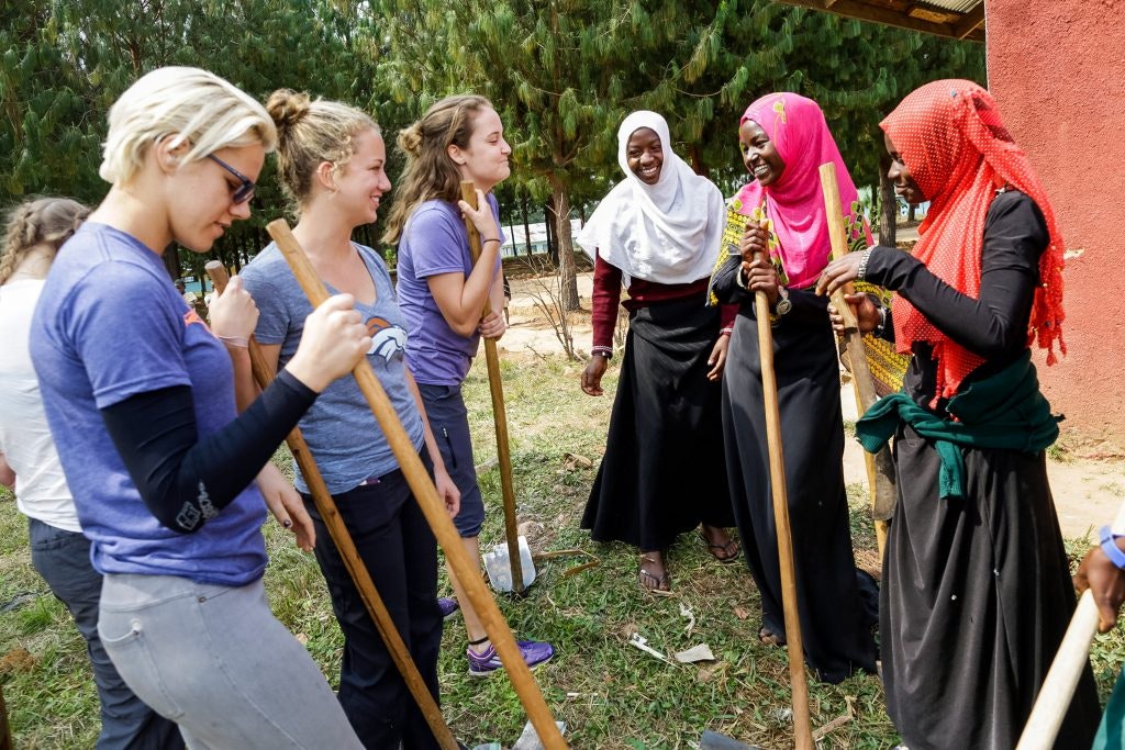high school students taking a break from service with local community members in Tanzania