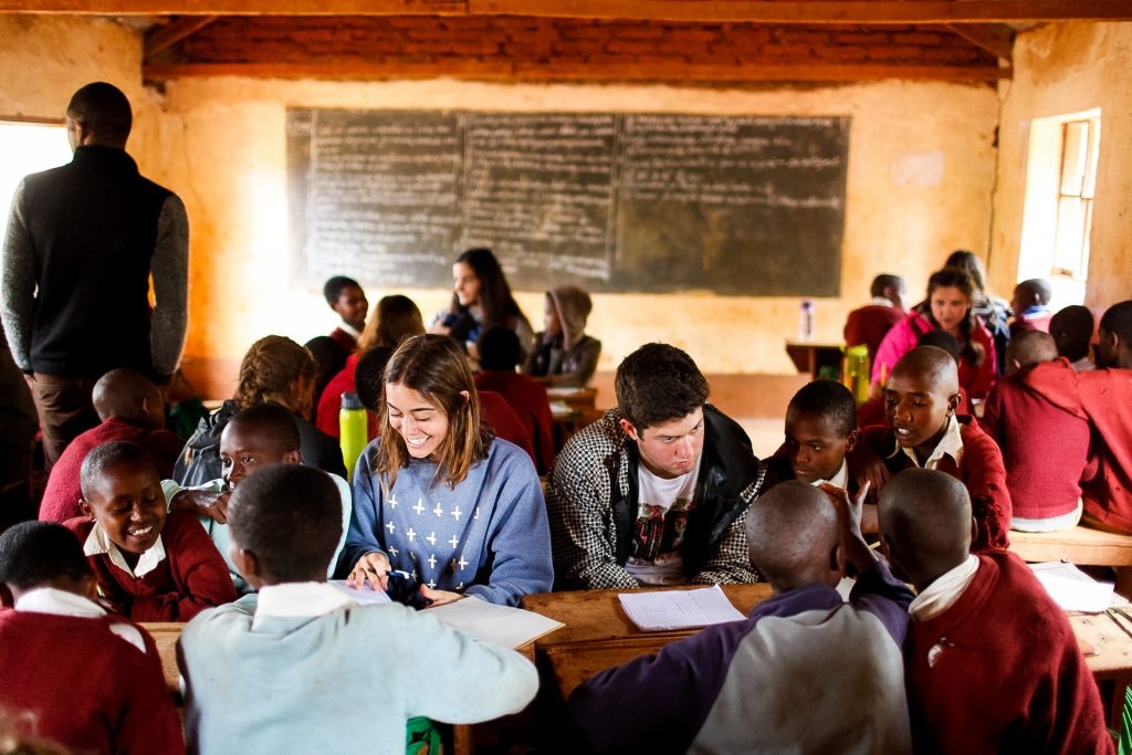 Teens engaging with local students in a classroom, sharing learning experiences.