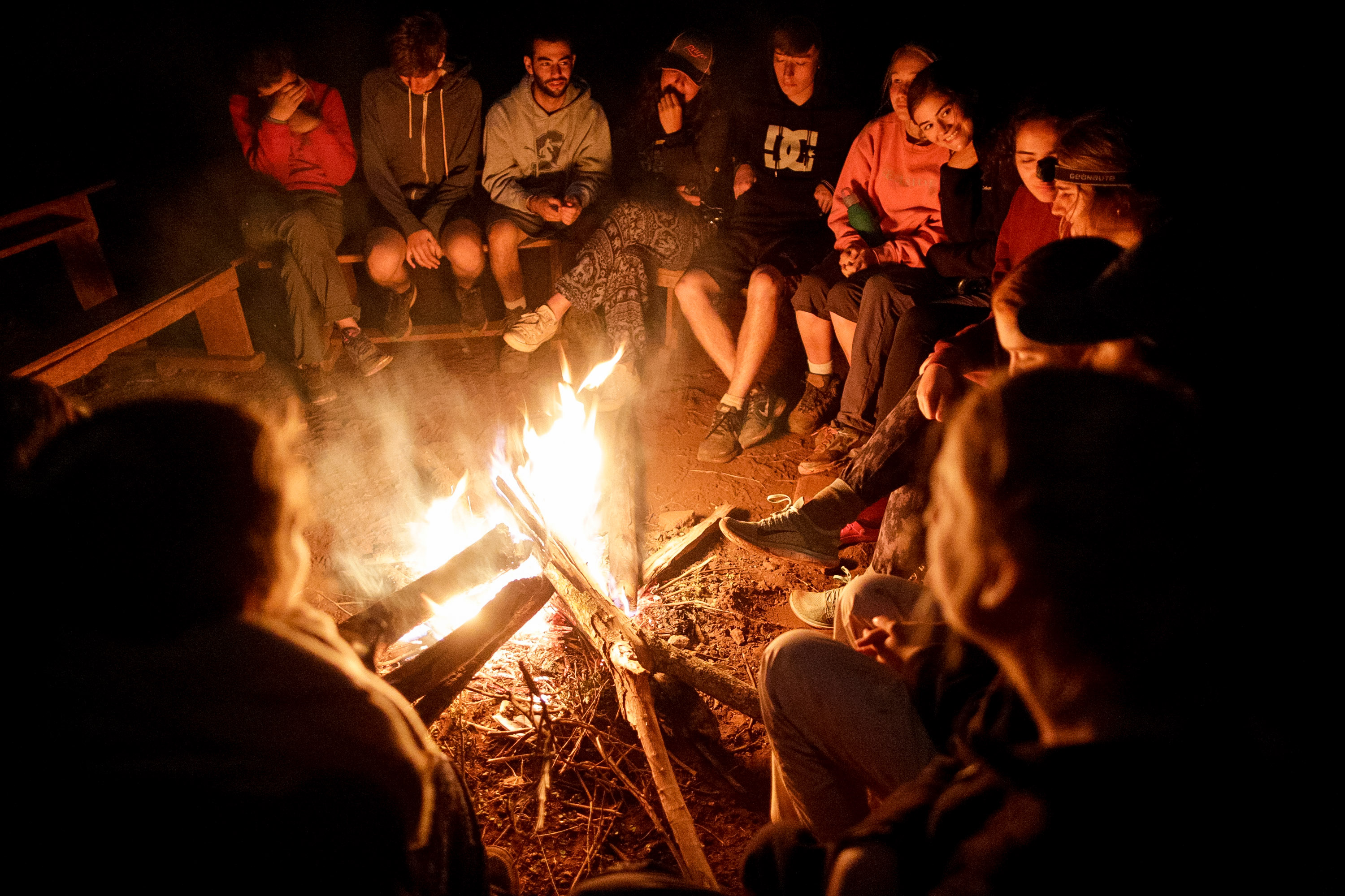 Students in Tanzania gather around a campfire at night