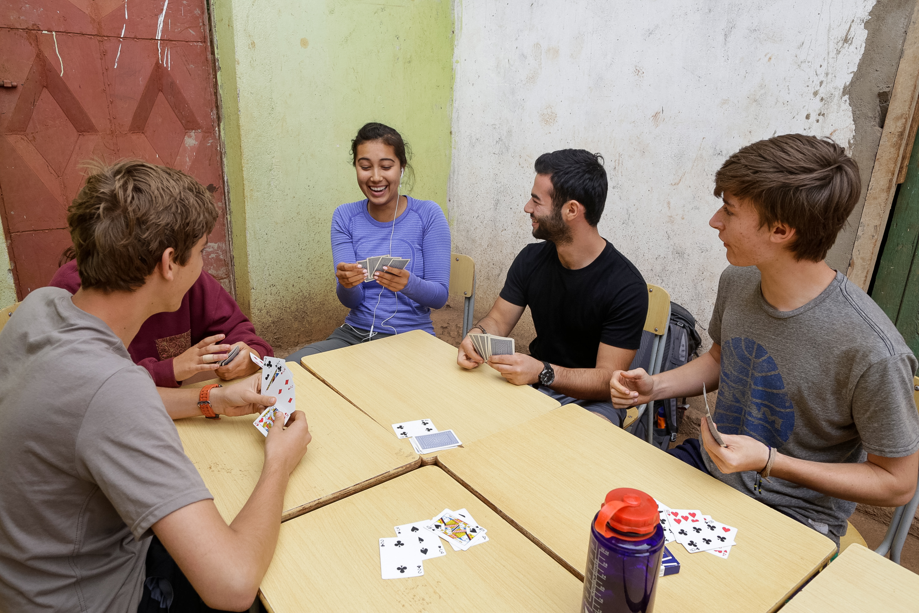 On a school trip, students laugh over a card game at an outdoor table