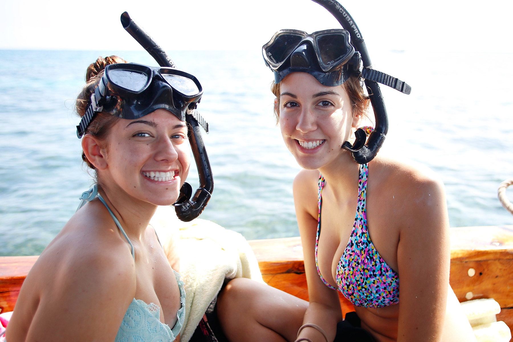 Students smile with snorkel masks pushed up on their foreheads aboard a boat