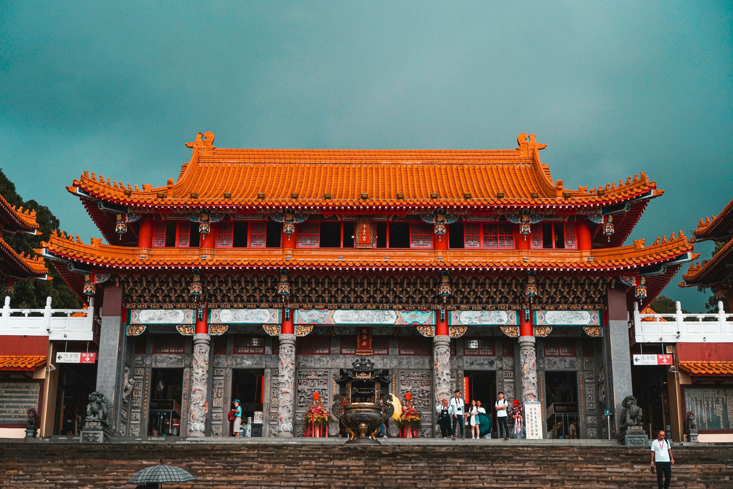 The orange-tiled roofs and carved stone columns of Wenwu Temple at Sun Moon Lake under a stormy sky.