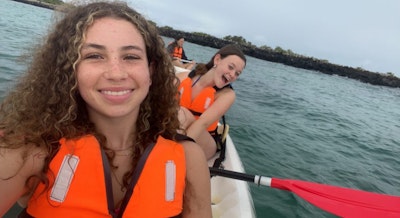 Teen travelers smile while kayaking in Ecuador during a teen tour.