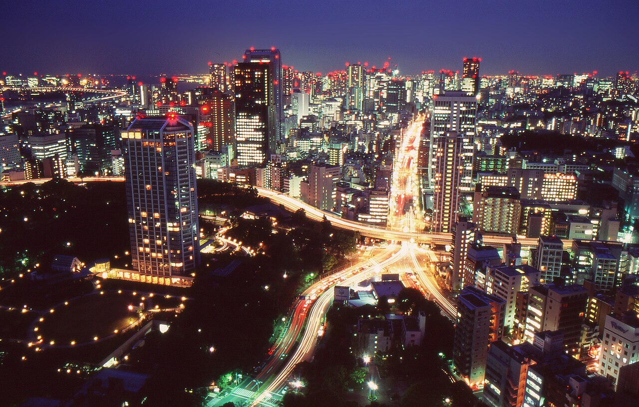 Student travelers take in the Tokyo skyline as it glows at night, with illuminated highways winding through the skyscrapers
